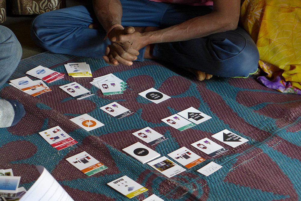 When interviewing a household, the researchers use cards representing various devices, the local microgrid, and the state-run electricity grid. Members of the household together recall the order in which they acquired their energy sources and lay down cards accordingly. At each decision point, the researchers ask why they made that choice. Credit: Ameya Athavankar